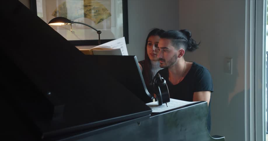 Man and woman sitting at baby grand piano