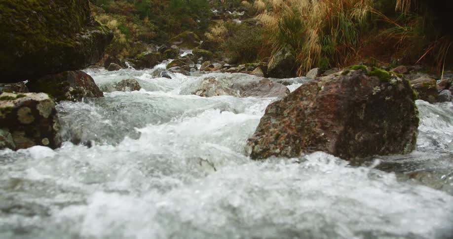 Water flows roughly in the stream by the rocks