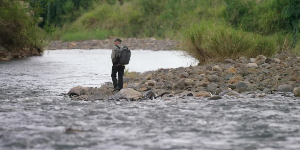 A man walks along a rocky riverbed