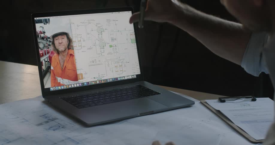 Engineer talks to construction worker through a laptop