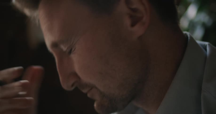 A man squints and rubs his eyes with a pen in his hand