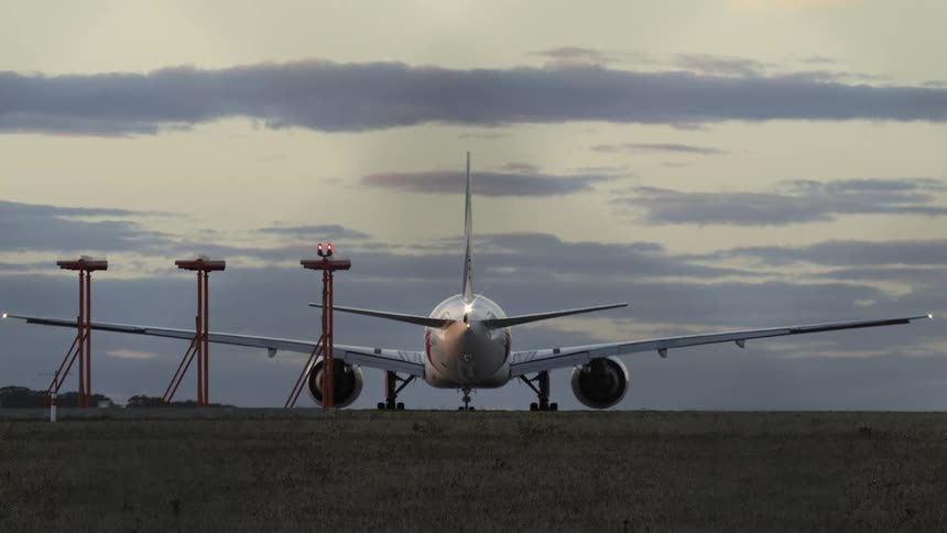 A plane parked with its landing get down outdoors in the evening