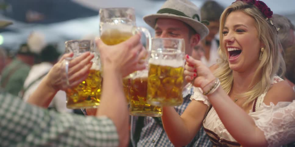 Men and women with lederhosen holding mugs of beer