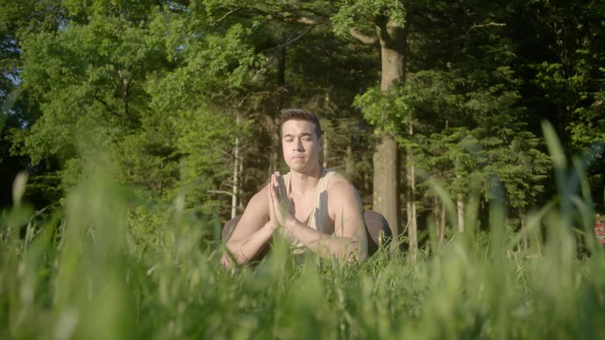A man sitting in a field of grass in a yoga posture
