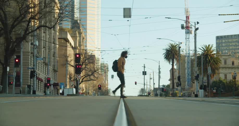 A man crosses the street at a city intersection near apartment buildings