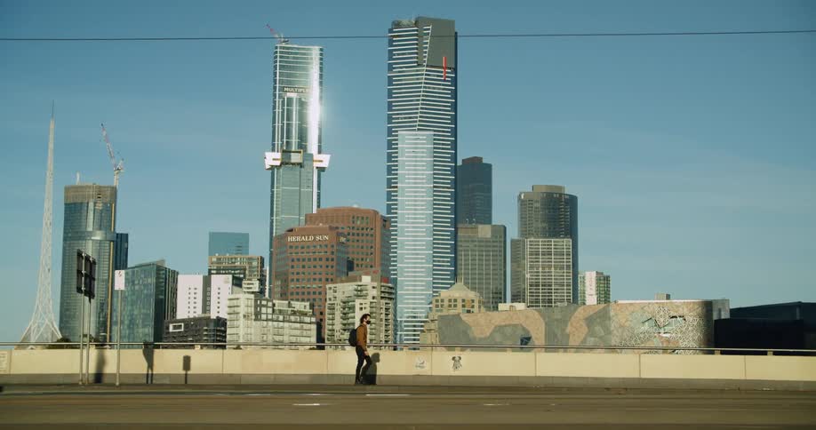 Man wearing face mask and jacket walks along empty highway near downtown