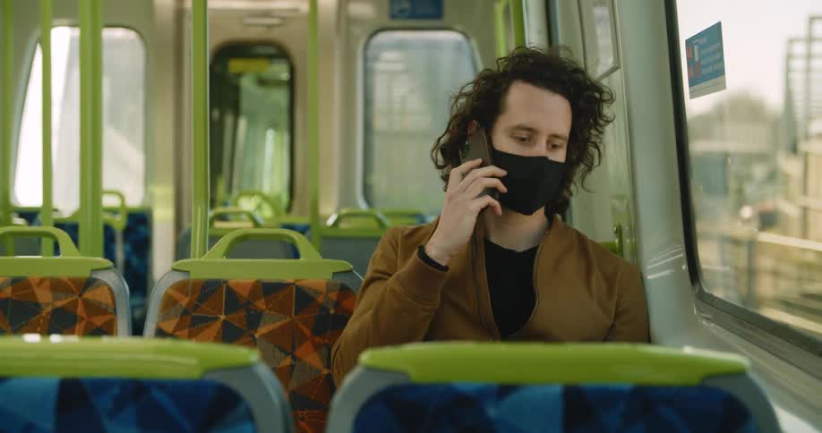 A man is talking on a phone while riding a city bus