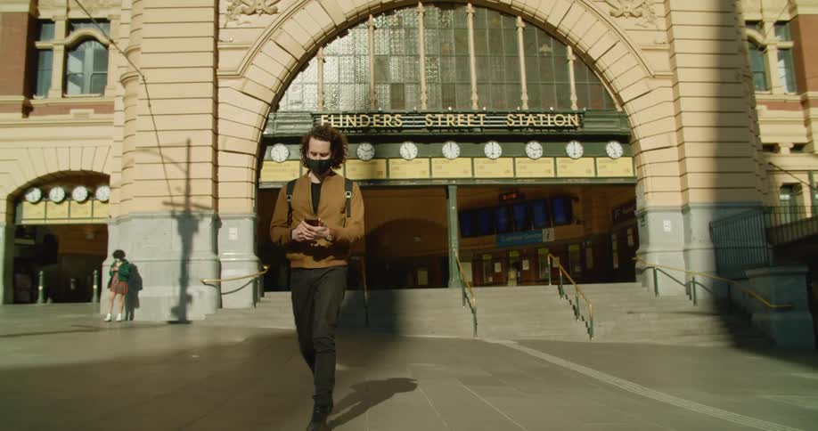 A man walks from the train station using his phone