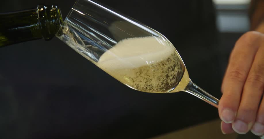 A bartender pours champagne into stemmed glasses