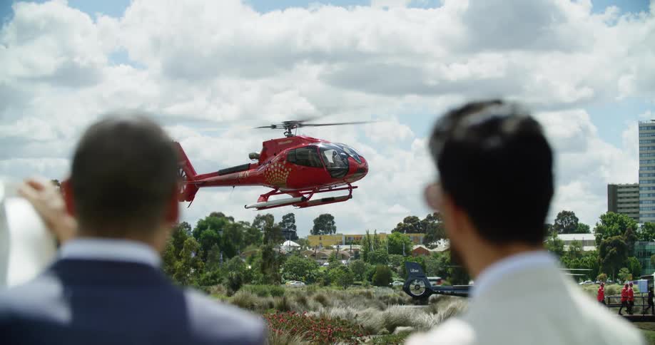 A man points to a helicopter rising up into a blue sky