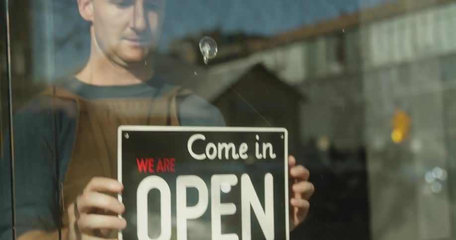 A worker changes a business sign from closed to open
