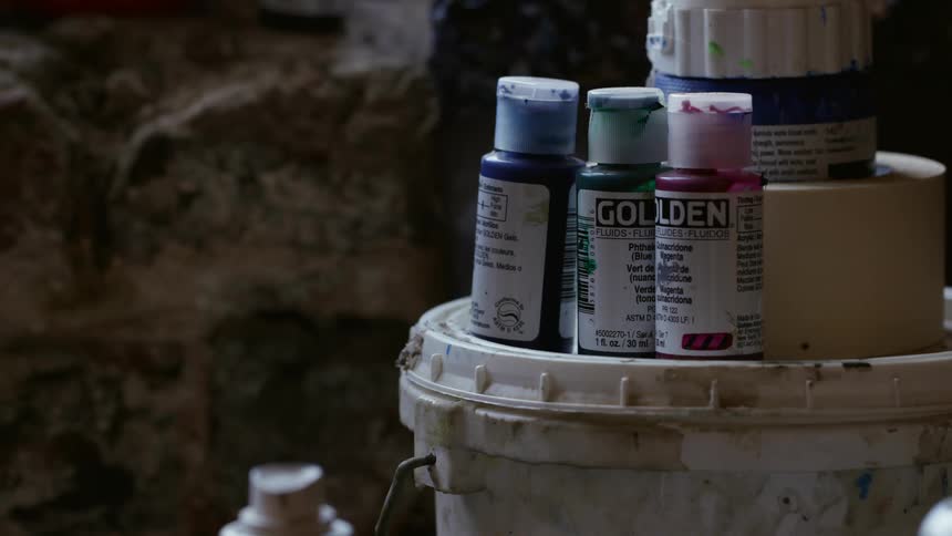 Small bottles of acrylic paint sitting on top of a bucket