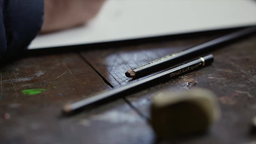A man uses a ruler to draw lines on large poster board