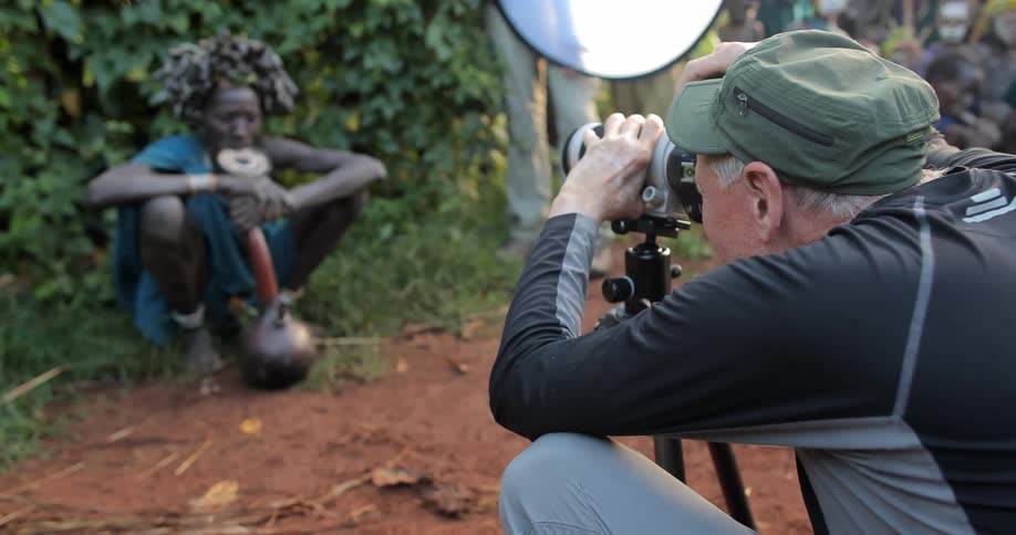 A man is crouching photographing a villager