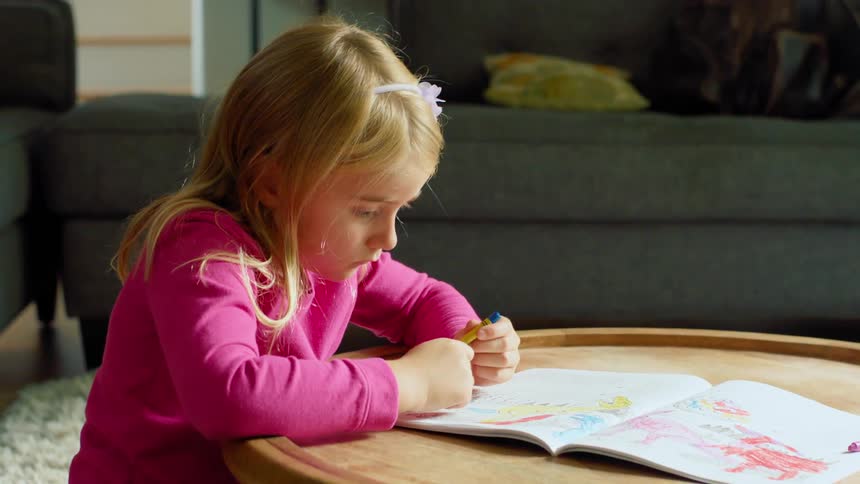A girl is coloring in the living room