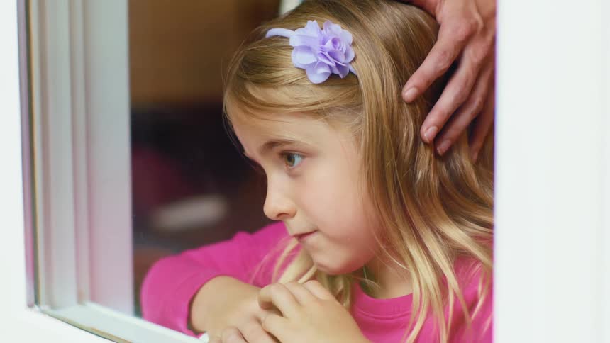 A daughter is looking out a window