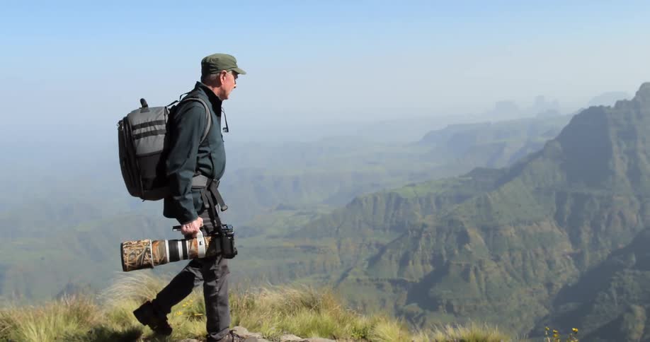 A photographer walking along a cliff