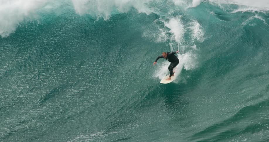A middle aged surfer attempts to ride a wave before falling off his surfboard