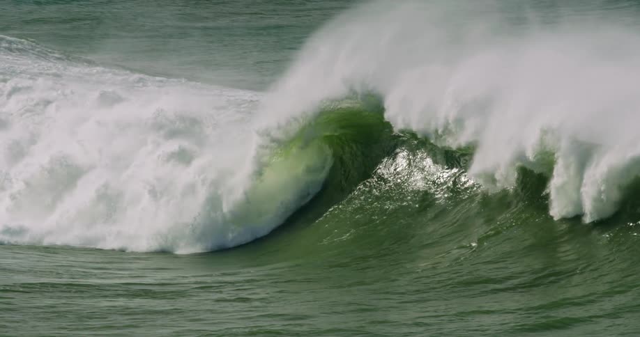 The large wave crashes on the rocks