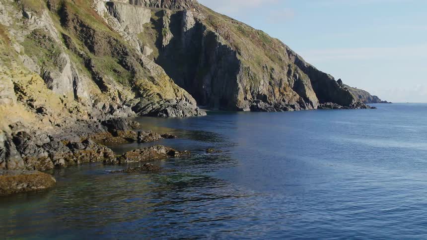Aerial view of calm sea waters in the rocky shoreline of a coast