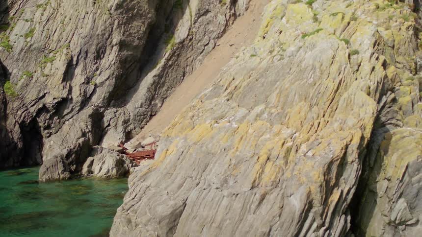 Wreckage of a metallic structure down the slope of a cliff near the ocean
