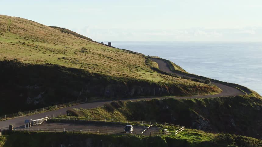 A road winds along the hills near the ocean shore