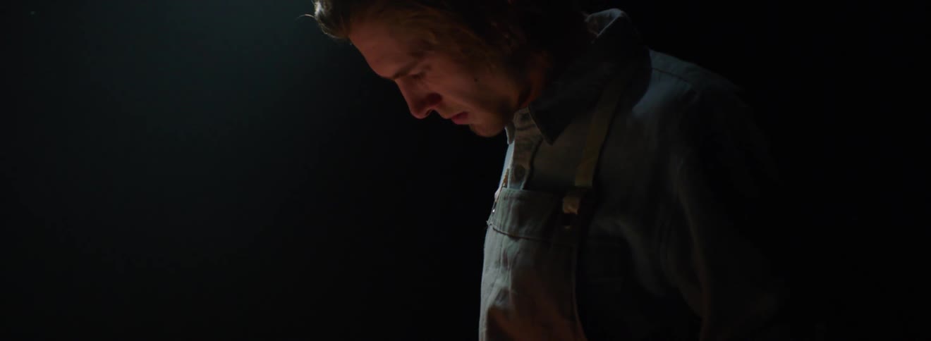 A man in front of a table and a cutting board looking at a knife