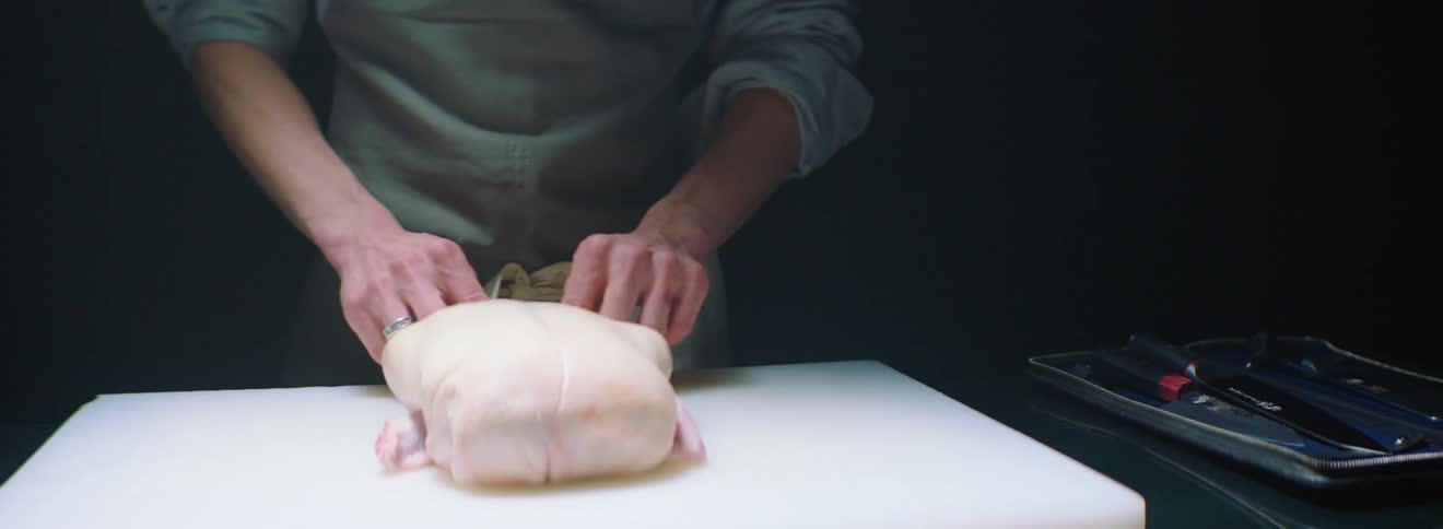 A man prepares a chicken on a cutting board