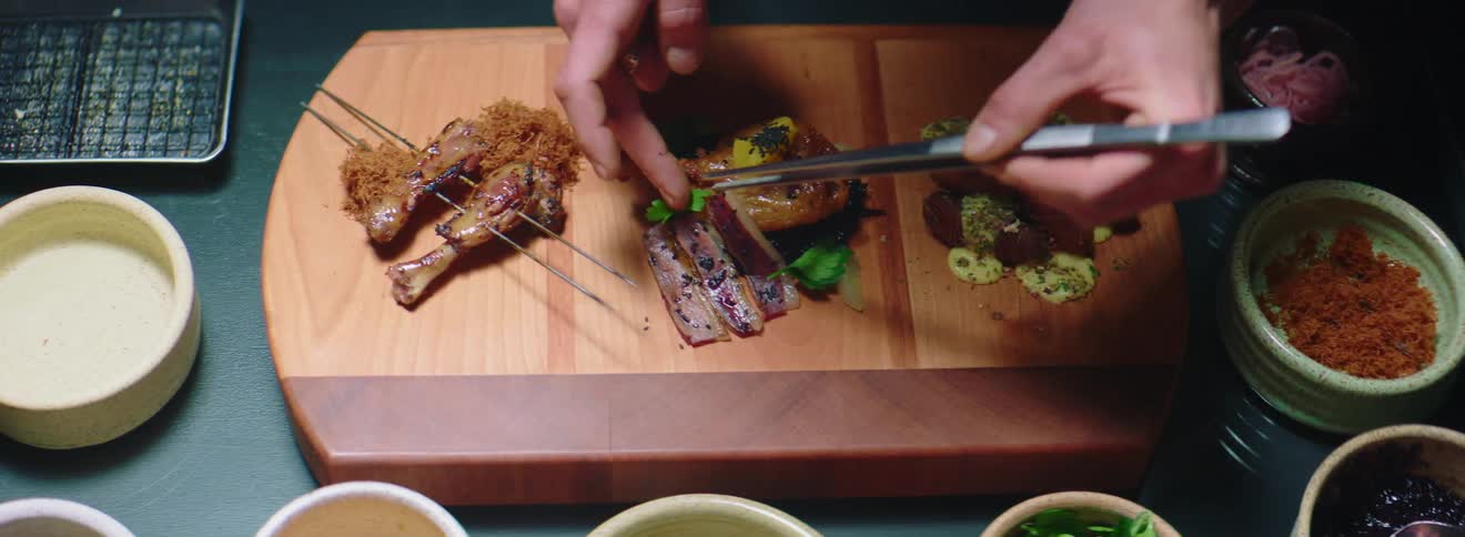 A man puts garnishes on a platter of food
