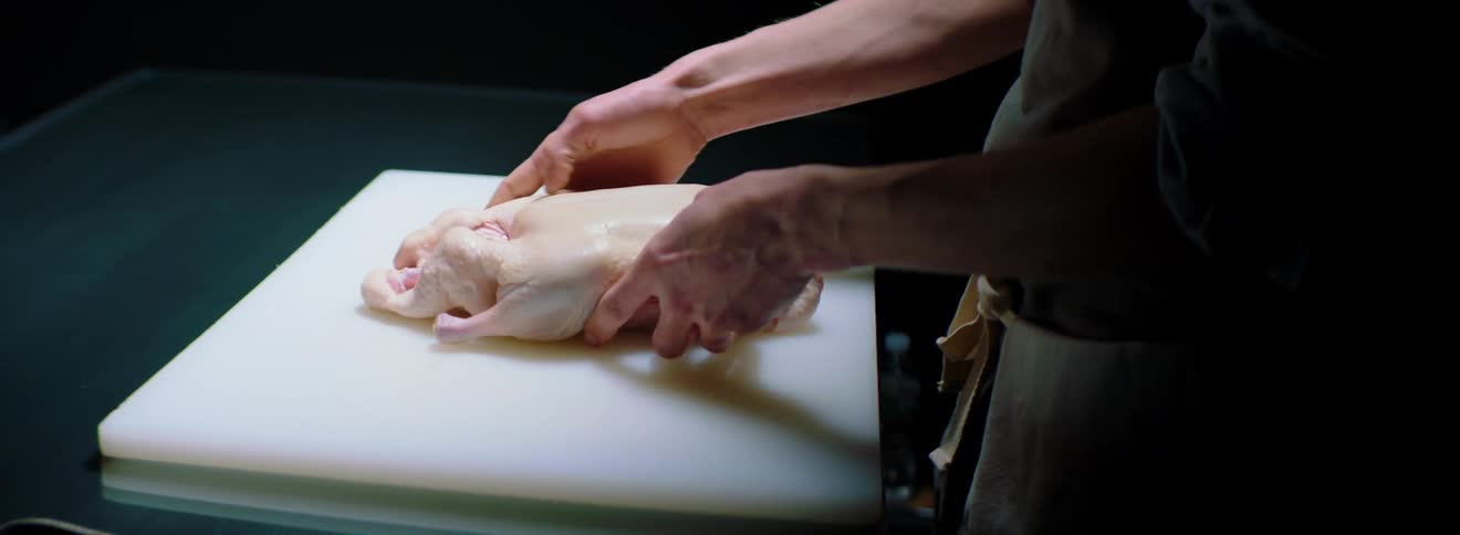 A man handles a raw piece of meat on a prep table
