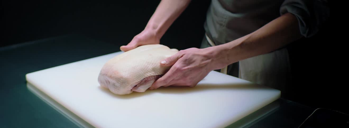 A person is preparing poultry on a table