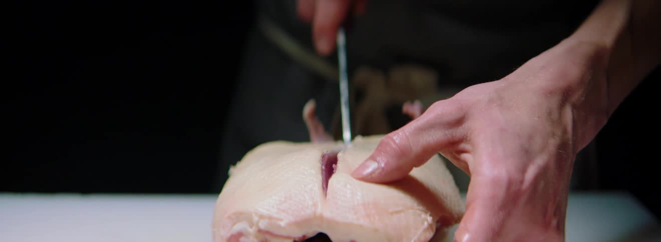 A white man cuts through a piece of food with a knife