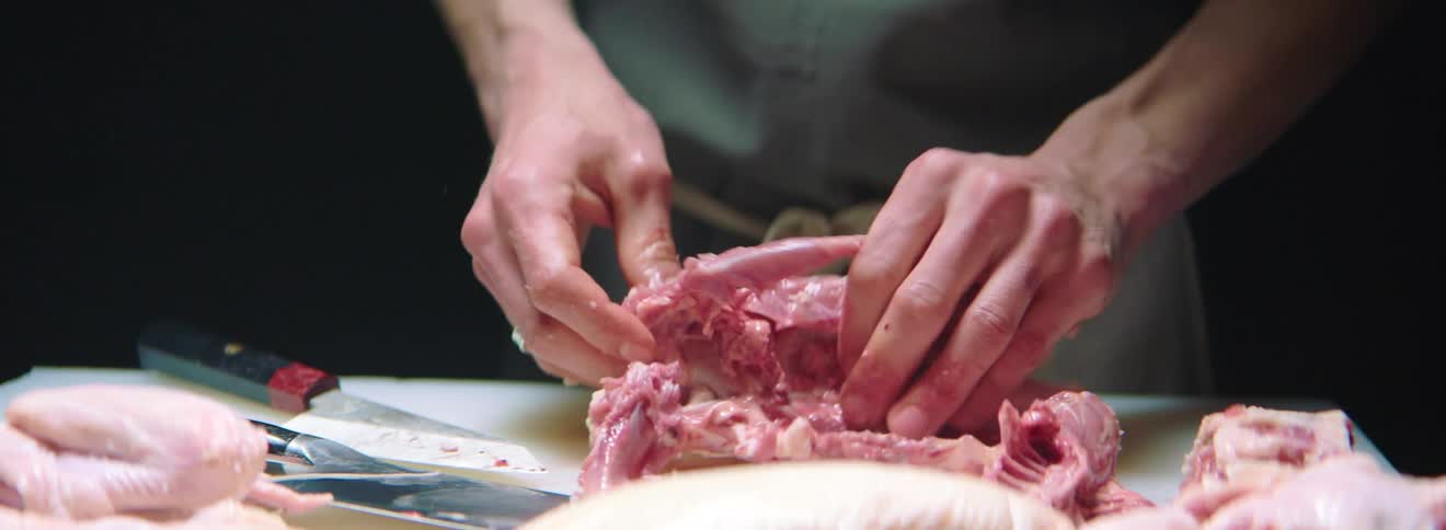 A white man pulls raw meat apart and then piles it together