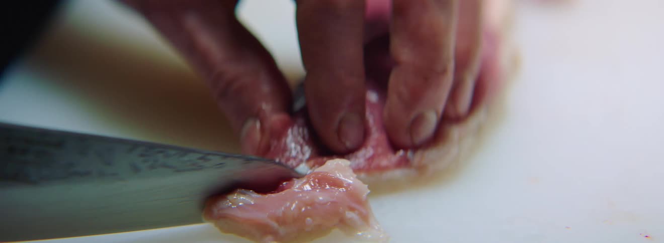 A white man slices a piece of raw meat