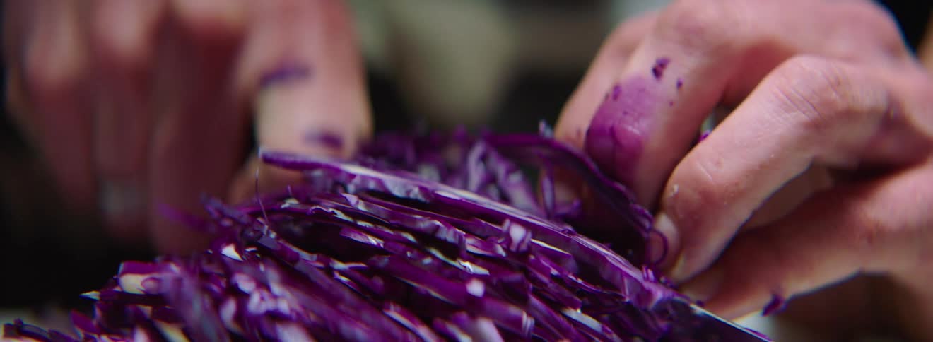 A person chops purple cabbage