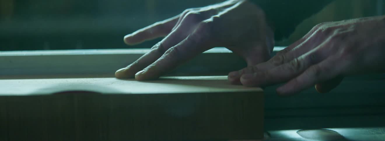 A wood worker runs a piece of wood across a table saw