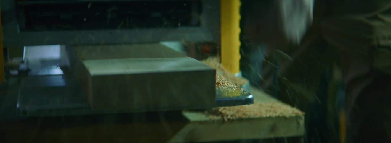 A person pulls a board out of a planer