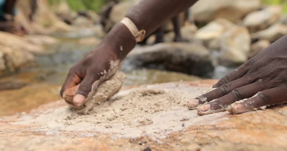 Someone is grinding with a rock by a stream