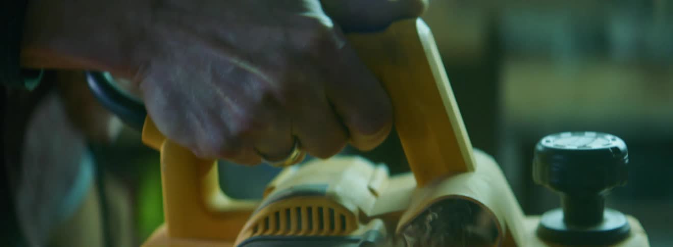 A man using a power sander on a wooden board