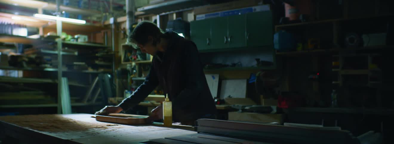 A young white man rubs a piece of wood with a rag