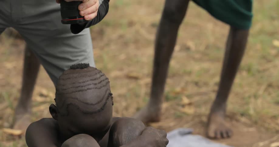 A man is being photographed while sitting on the ground