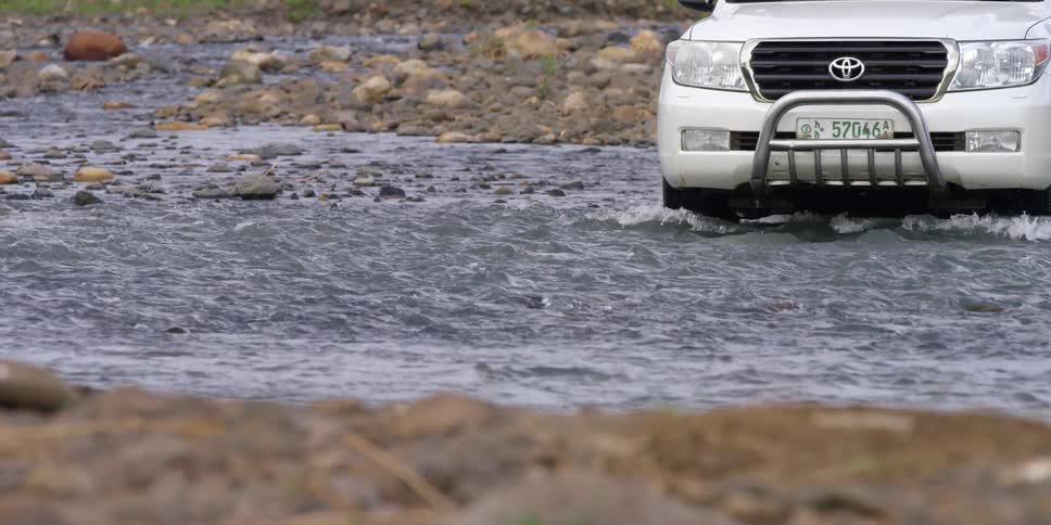 A vehicle is driving over a stream