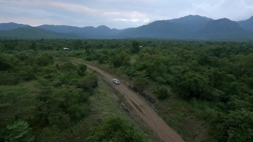 A car is driving uphill on a dirt trail