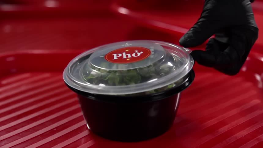A person puts a lid on a container of pho