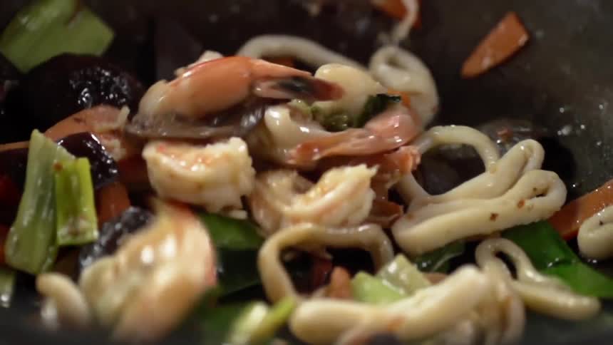 Seafood falling inside a in a wok over cooked vegetables