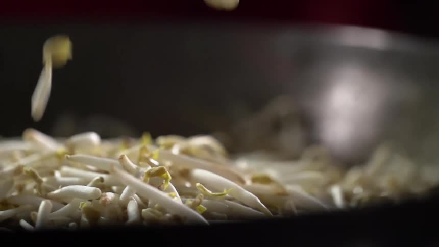 Bean sprouts dropping into a pile in a saute pan