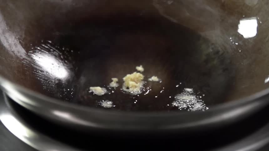Oil sizzling in a pan as garlic is dropped in