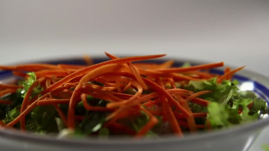 Vegetables are being dropped on the salad bowl