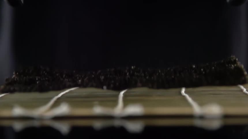 A person puts a nori wrap on a sushi mat