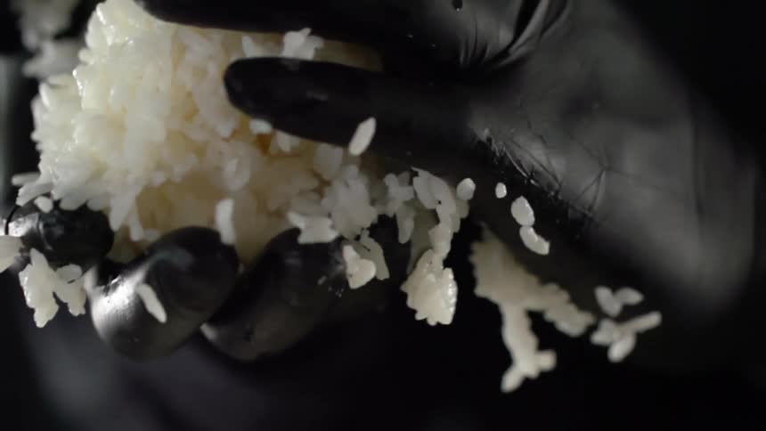 A person with rice in their gloved hands